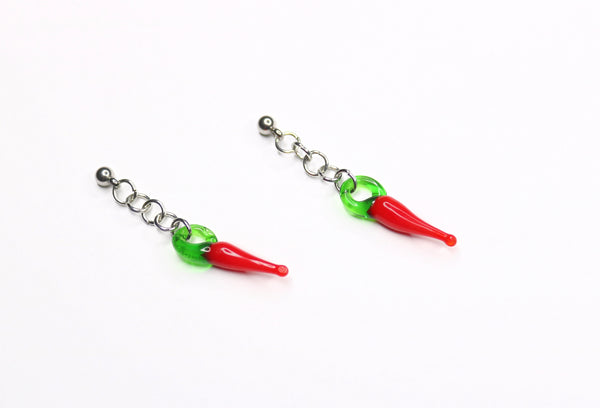 pair of earrings with silver studs and glass red chili pepper charms attached with a short chain